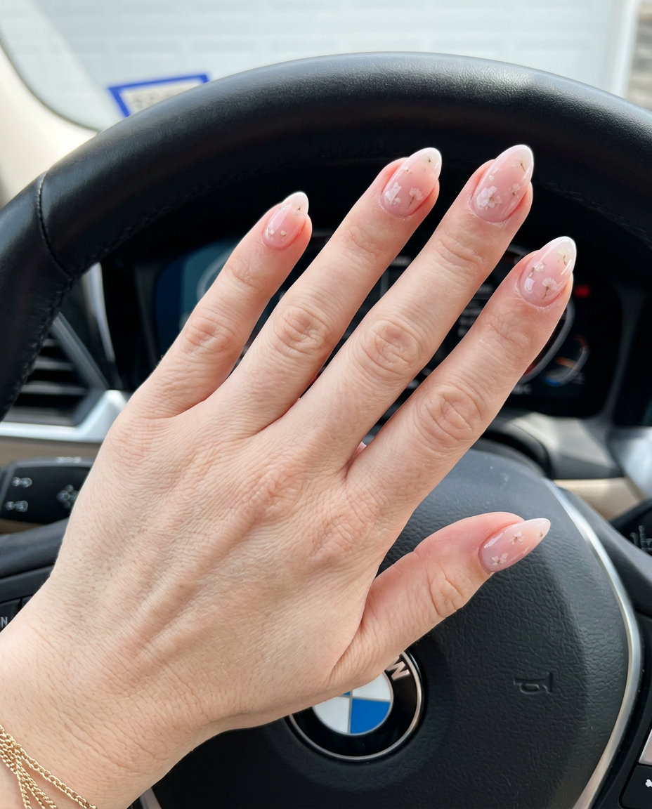 Sheer Pink Floral Almond Nails 2026 Sheer pink milk bath almond nails with floral inclusions for fair skin, ideal for weddings.