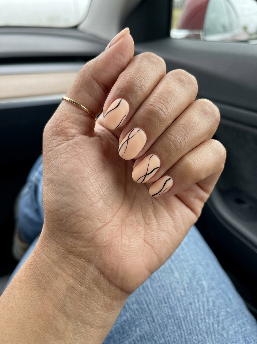 Short oval summer nails 2026: Creamy peachy keen gel with black abstract lines, matte finish. Perfect for casual days.