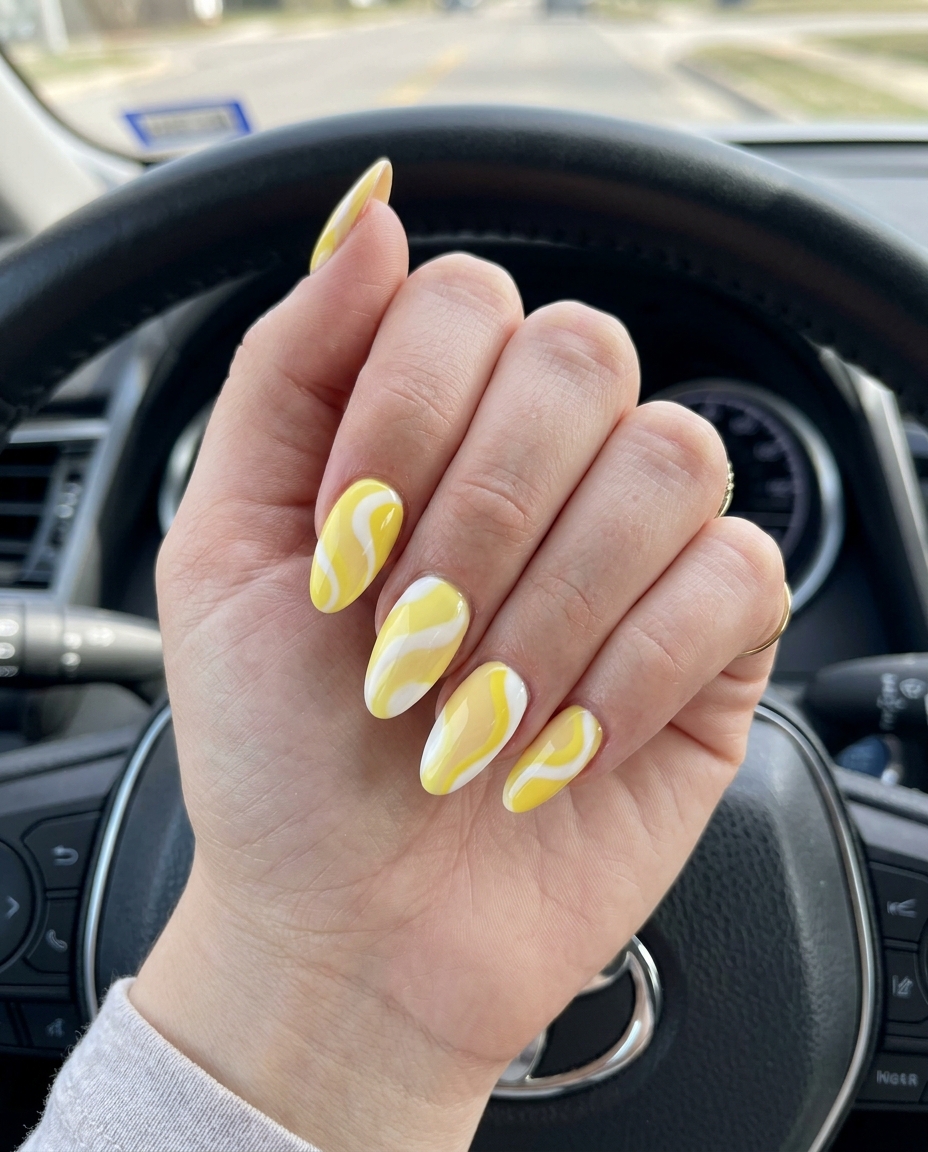 Artistic butter yellow swirls on almond nails for vacation & parties, simple summer acrylic nail designs 2026.