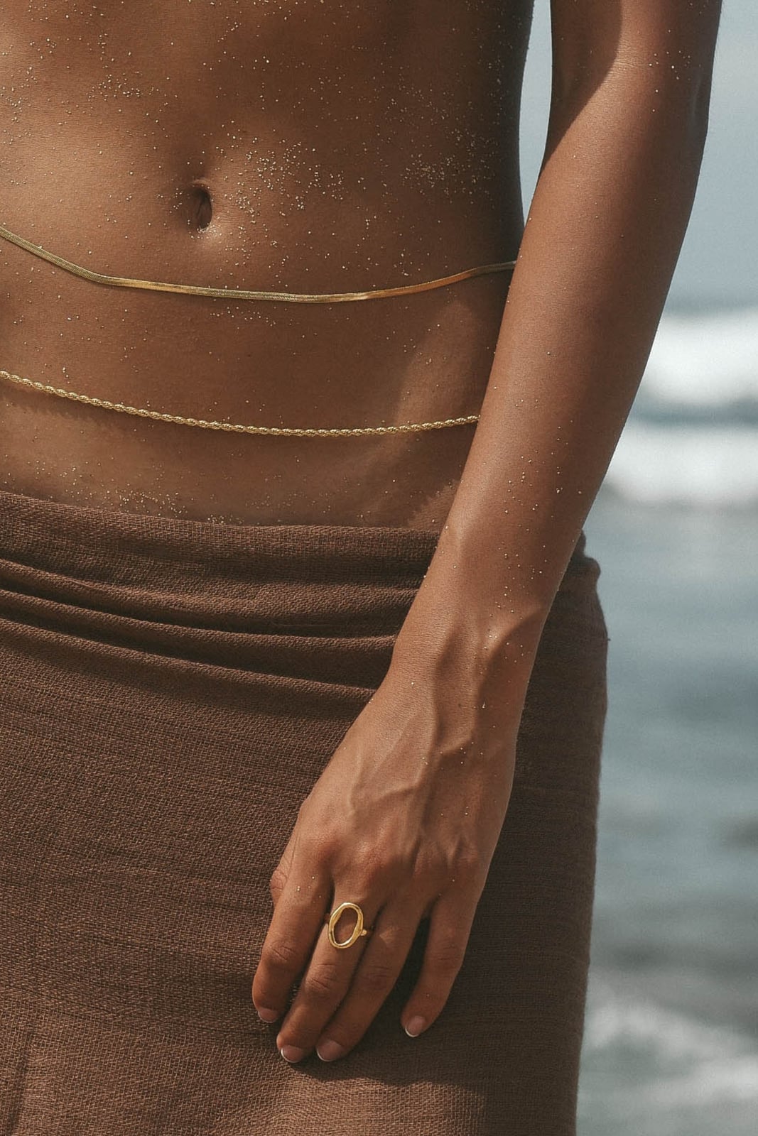 Delicate gold body chains with brown wrap skirt on beach Delicate gold body chains with brown wrap skirt on beach — Body Chain Outfits 2027