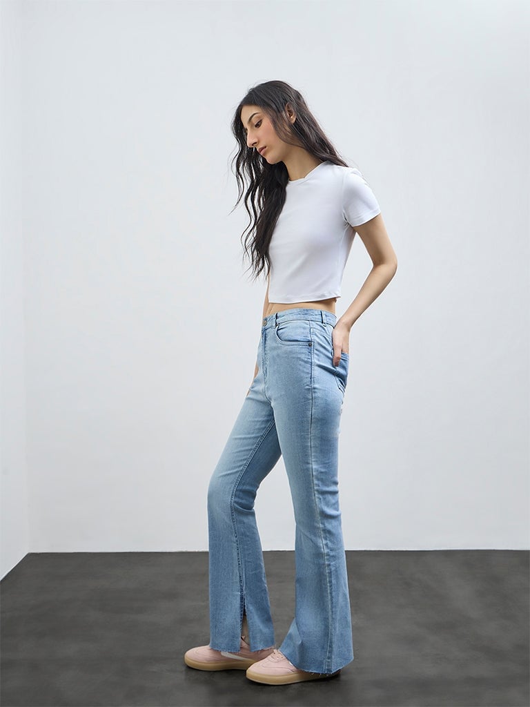 Light blue flared jeans with a white cropped tee and pink sneakers — Concert Bootcut Jeans Outfits 2027