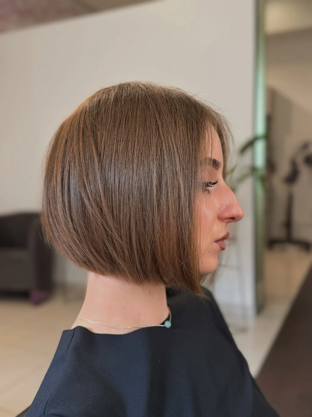 A Compact Bob Defined by Its Side Profile Smooth brunette bob with rounded profile and slightly longer front edge