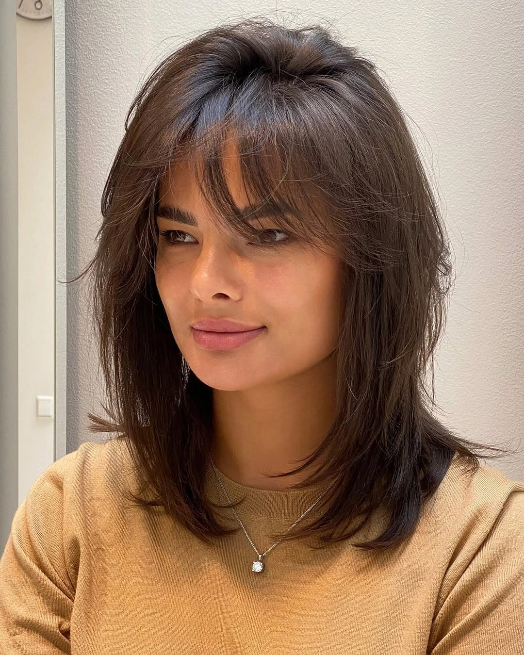 Wispy Fringe Gives Medium Layers More Character Dark shoulder-length haircut with wispy fringe and textured layers