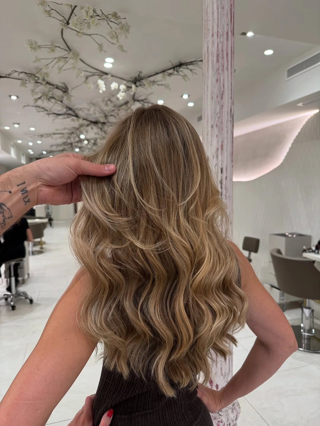 Blended Layers Create a Softer Back Taper Long blonde hair with loose waves and softly tapered layers