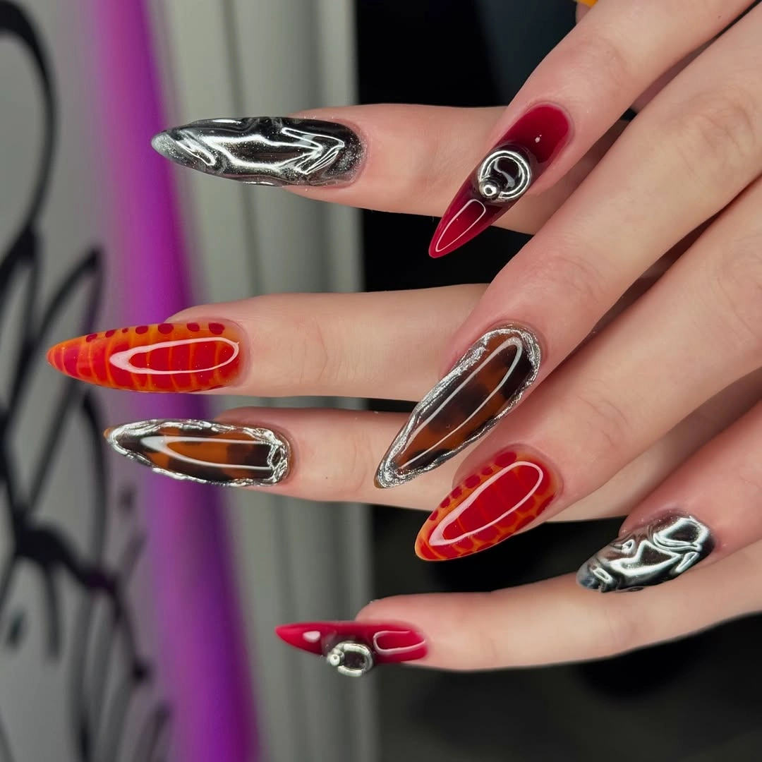 Futuristic Red Nails With Mirror-Silver Framing Long pointed red and orange nails with mirror-silver abstract details