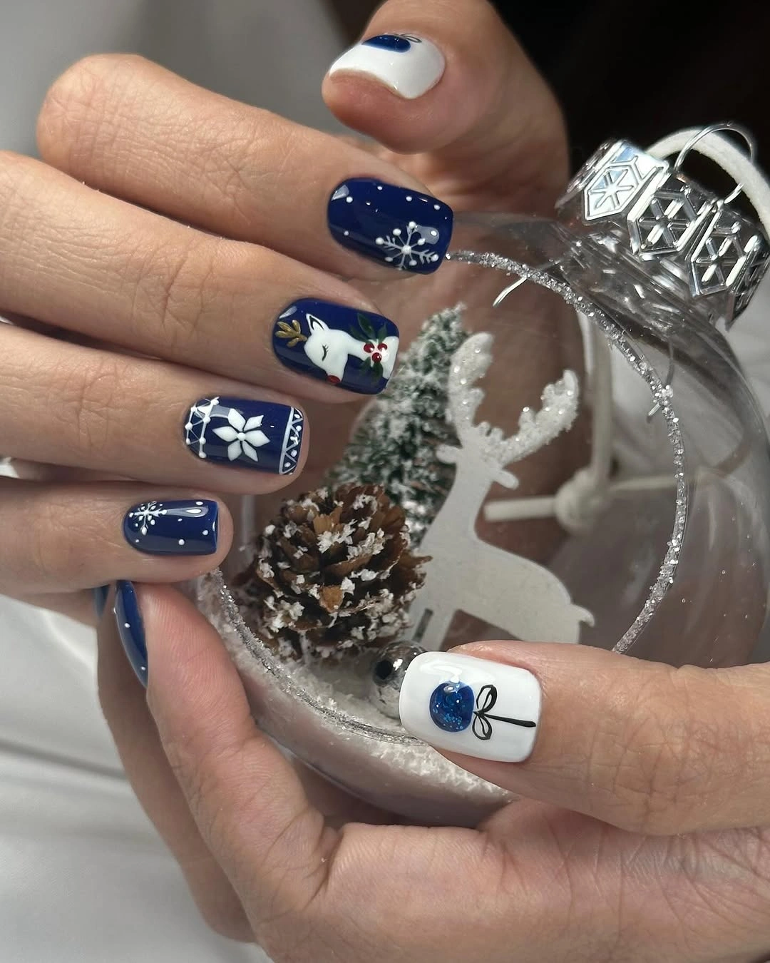 Navy Christmas Nail Art on Short Squares Short navy and white nails with reindeer, ornament, and snowflake art