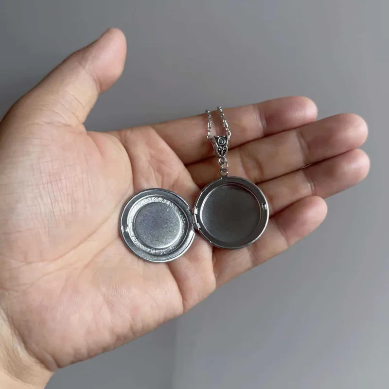 Open Round Silver-Toned Locket Displayed in Hand Open Round Silver-Toned Locket Displayed in Hand — Locket Necklaces 2027