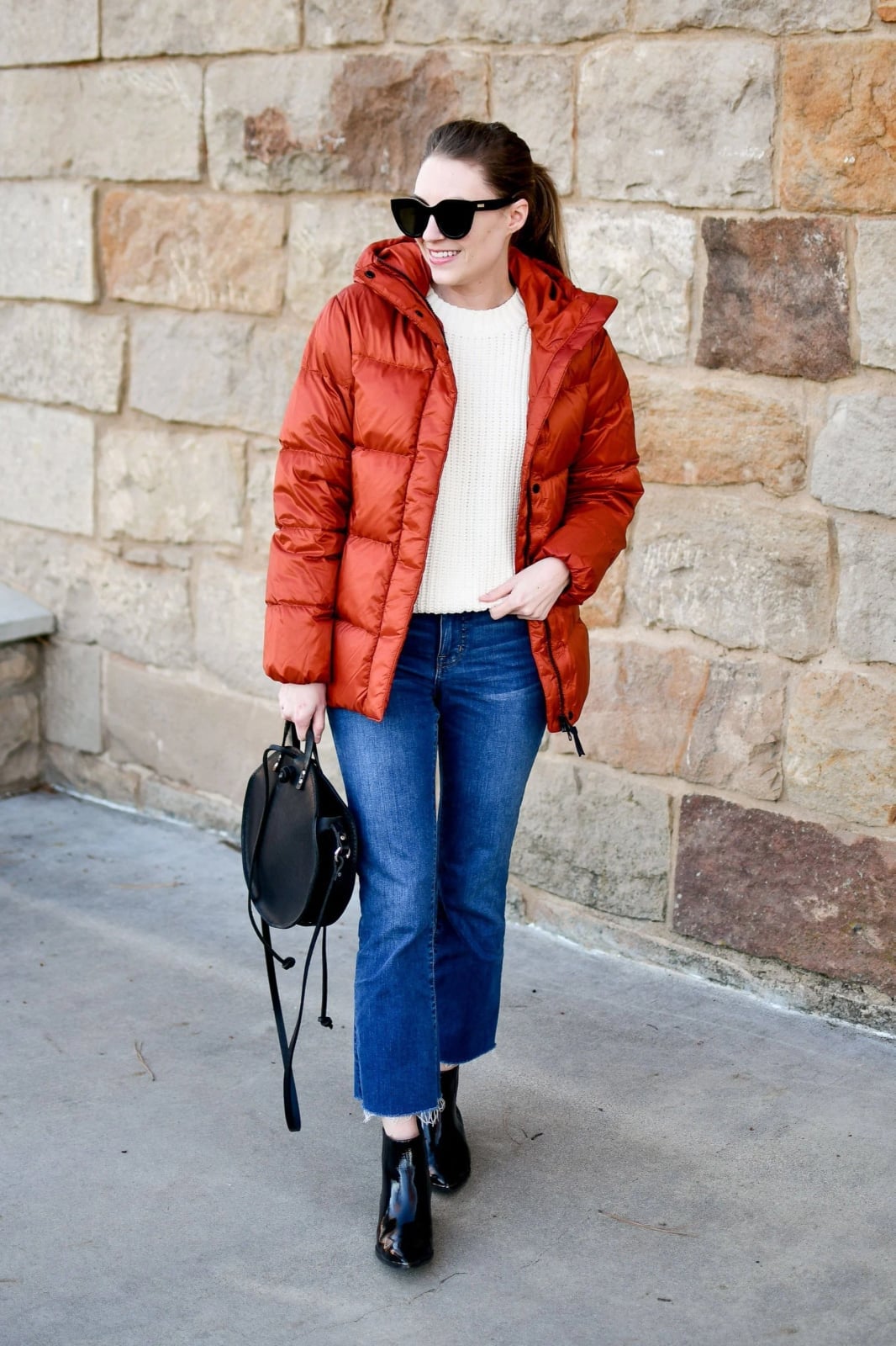 Orange puffer jacket over cream knit sweater and jeans Orange puffer jacket over cream knit sweater and jeans — Winter to Spring Transition Outfits 2027